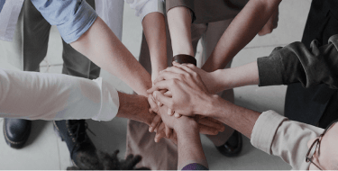 Estudantes fazendo um circulo com as uma sobre as outras no centro.
